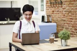 Smiling woman in loft apartment looking down at her laptop