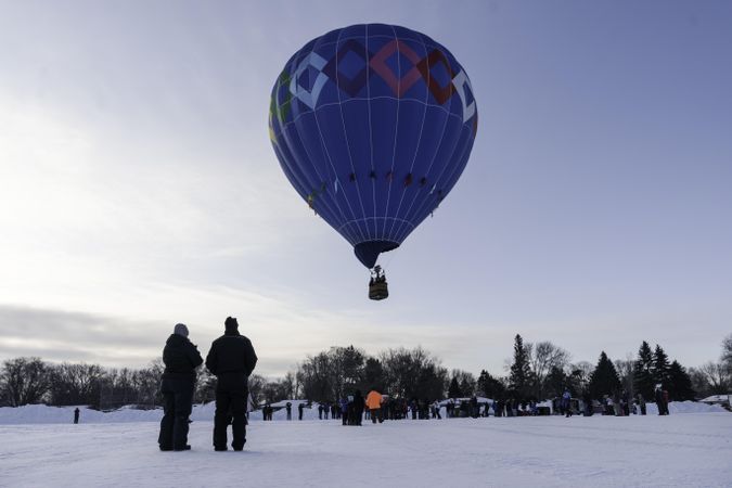 Hudson, WI, USA - February 8th, 2020: A blue hot air balloon lifting off on a winters day