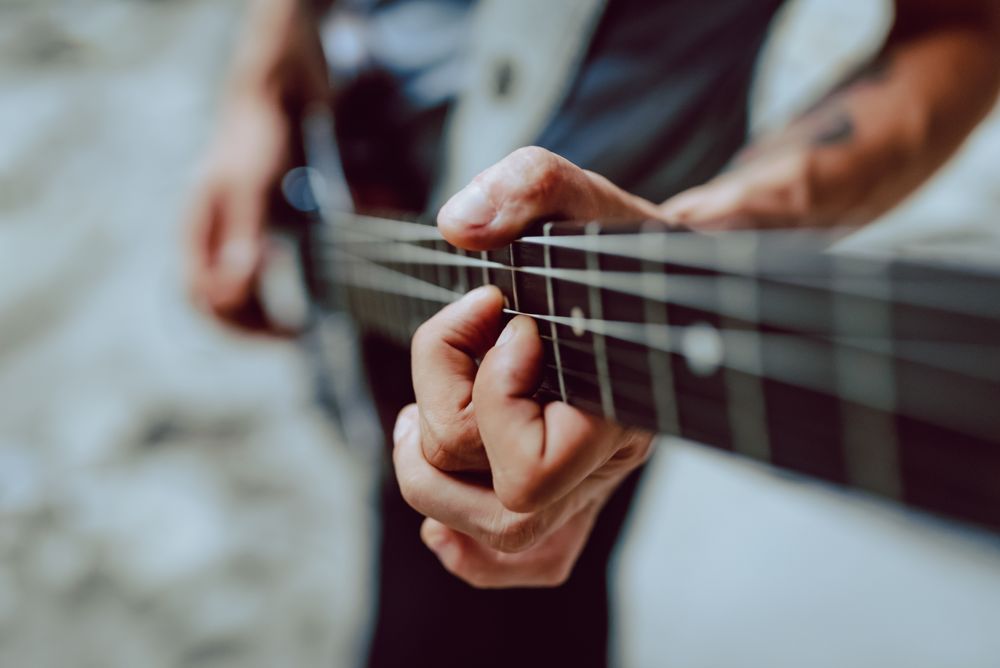 Man clamping strings on guitar neck