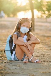 Positive girl in mask listening to music in forest