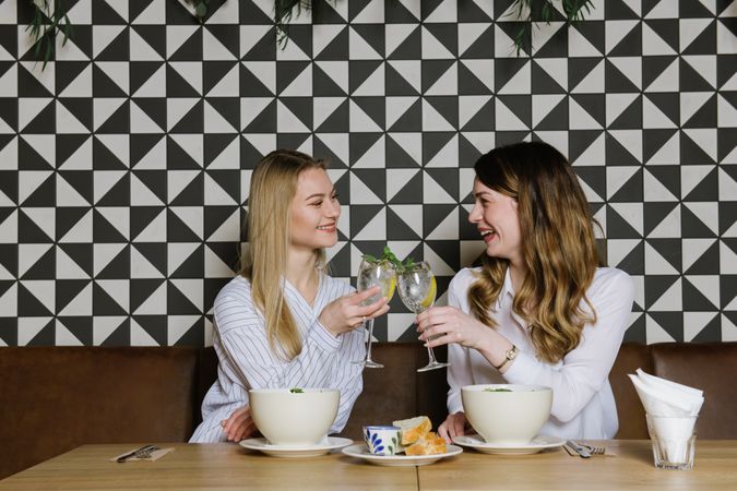 Cheerful friends clinking glasses in cafe