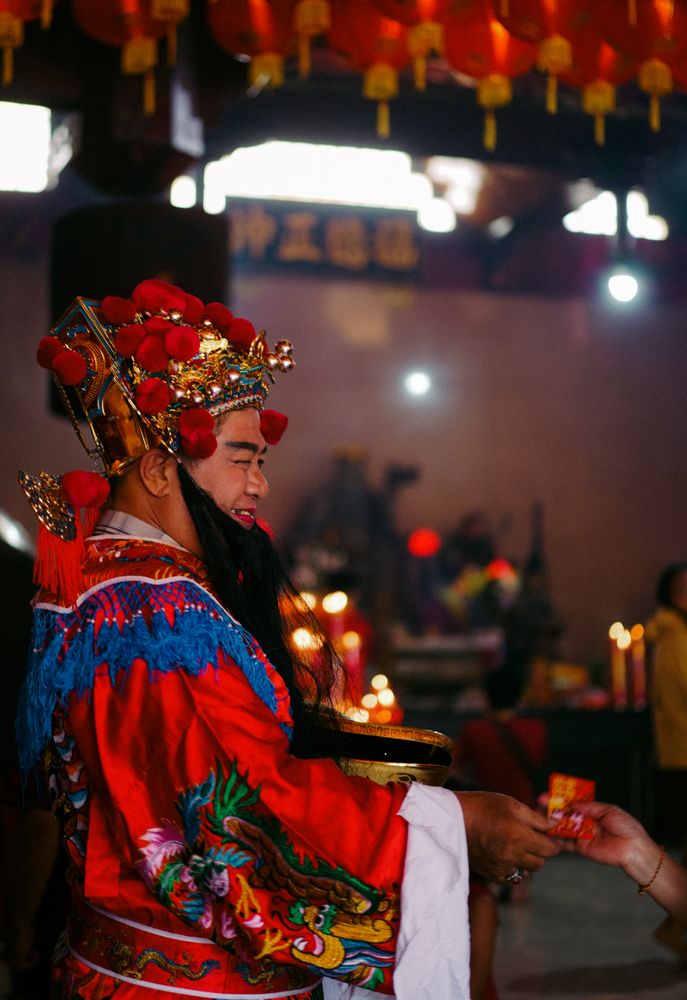 Side view of a man in red Chinese outfit in temple during Chinese New year praying event