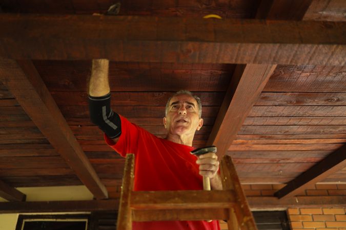 Older man working on his roof.