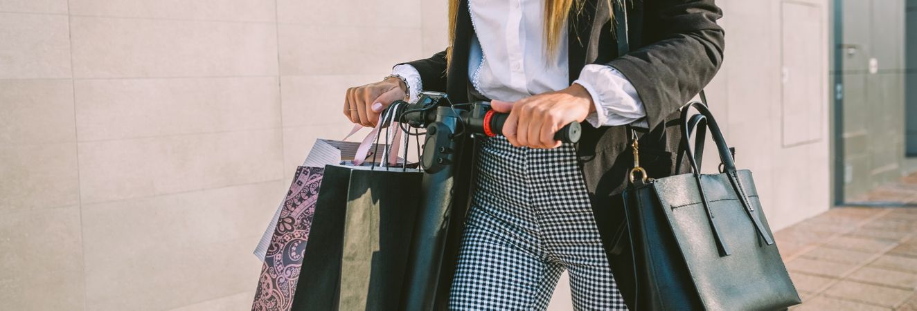 Unrecognizable woman with shopping bags on electric scooter