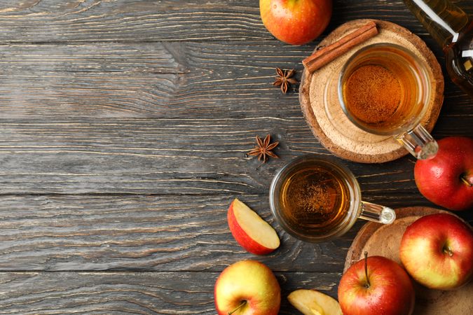 Composition with cider, cinnamon and apples on wooden background