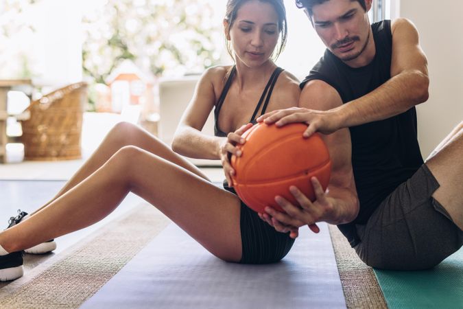 Fitness couple doing exercises with a medicine ball at home