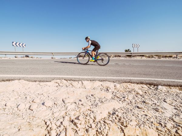 healthy man riding a bicycle on a mountain road in a sunny day