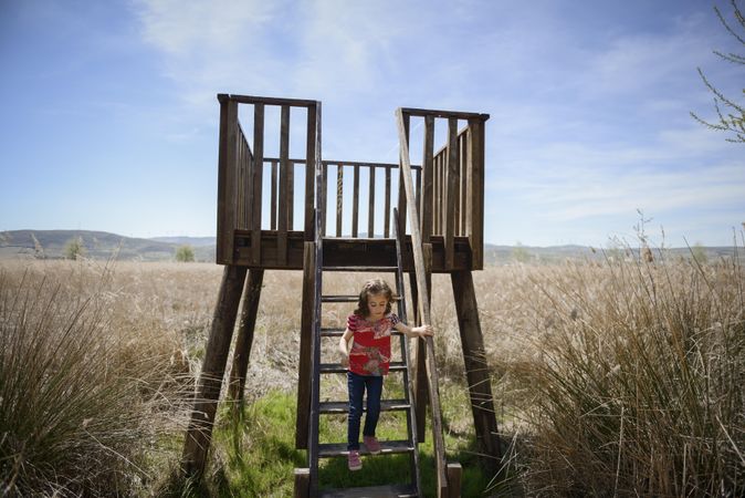 Field with wooden stairs with child climbing down