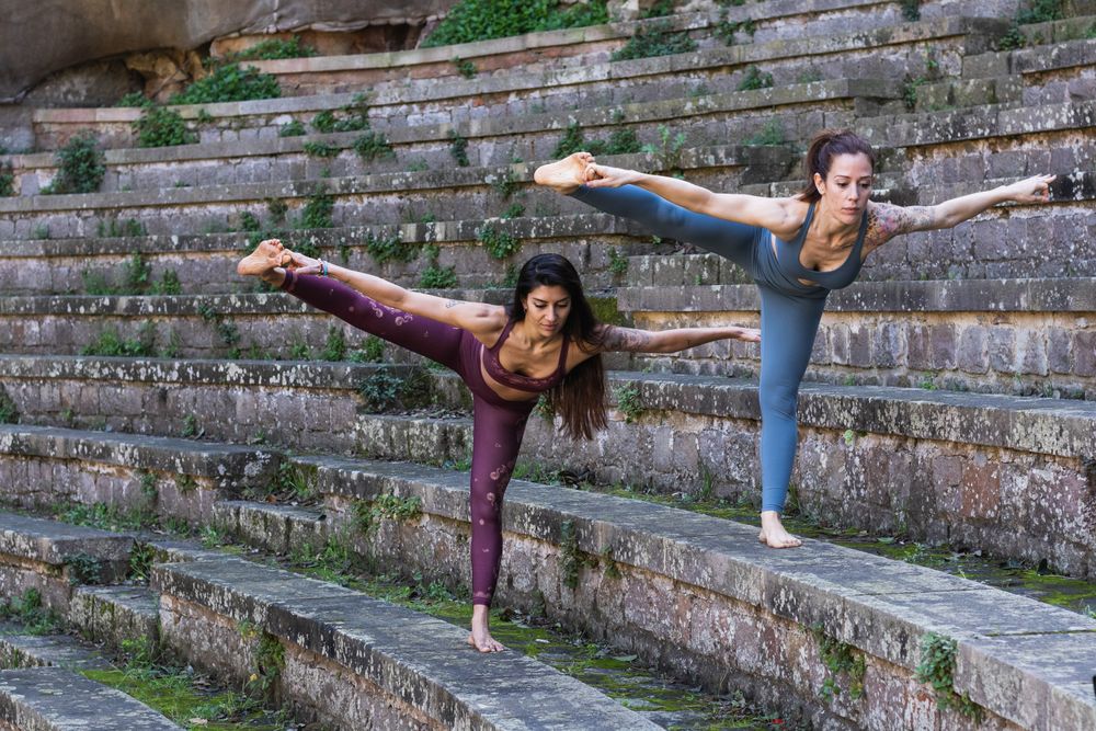 Focused women standing in Hand to Toe pose and doing yoga