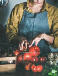 Woman in yellow sorting tomatoes from wire basket