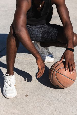 Confident Black sportsman on basketball court in summer