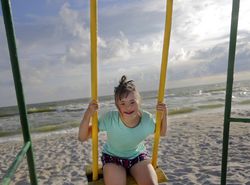 Smiling girl having fun on swing set at beach