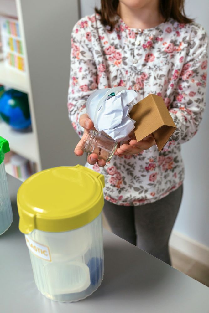 Girl in ecology classroom showing handful of waste to recycle
