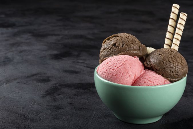 Bowl with Neapolitan ice cream on dark background.