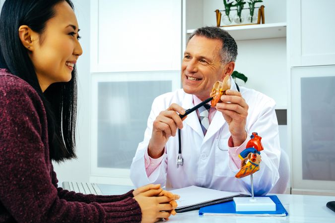 Smiling male doctor with female patient consulting about heart structure