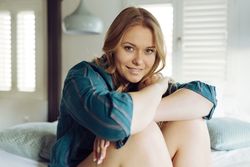 Young happy female sitting on bed