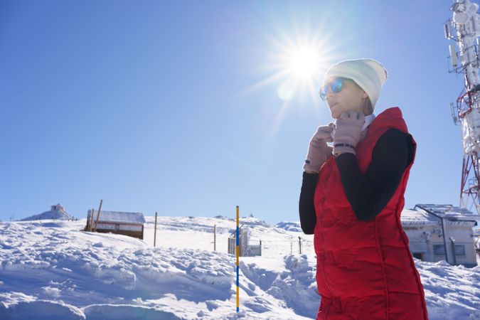 Woman in warm sportswear putting headphones in winter
