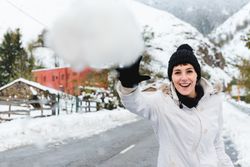 Smiling woman playing with snow in countryside