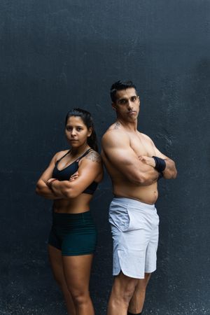 Serious Hispanic sportive couple near wall