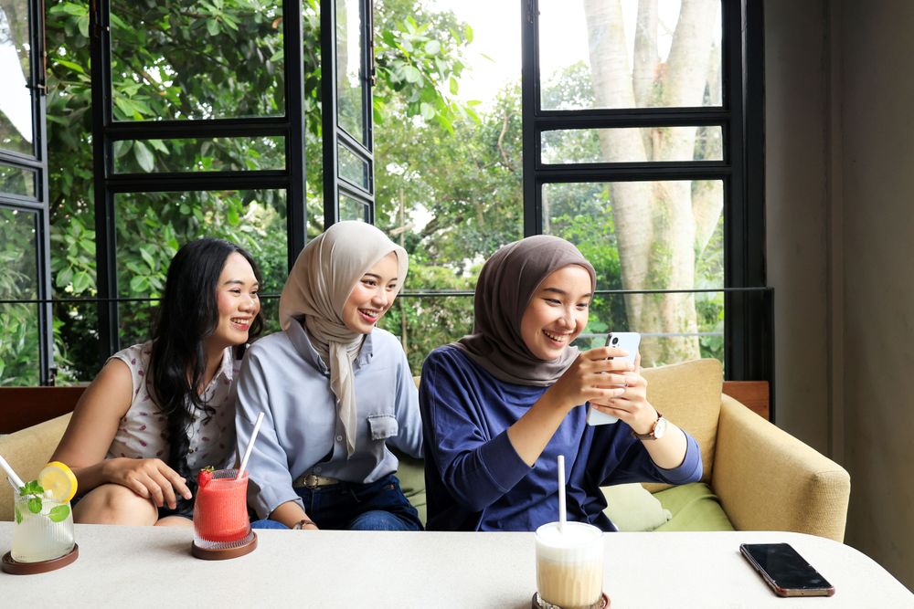 Three Asian friends Hanging Out at cafe restaurant, Looking at Mobile Phone