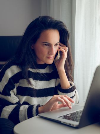 Concentrated female freelancer using laptop and talking o