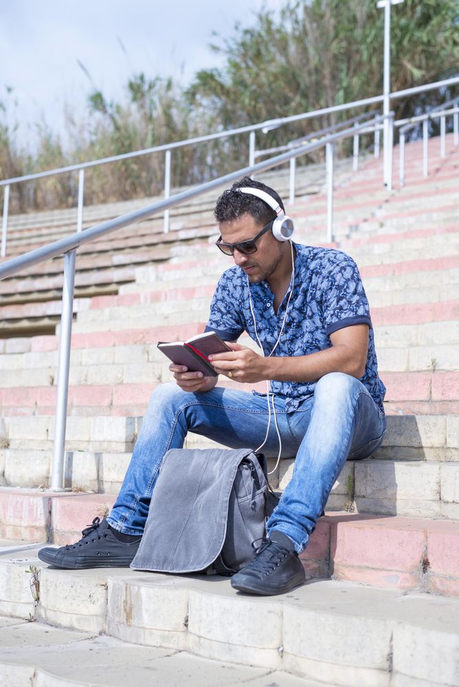 Male sitting on outdoors steps and reading