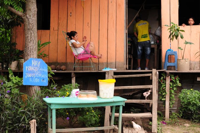 Woman sitting on a chair outside a wooden house in Brazil