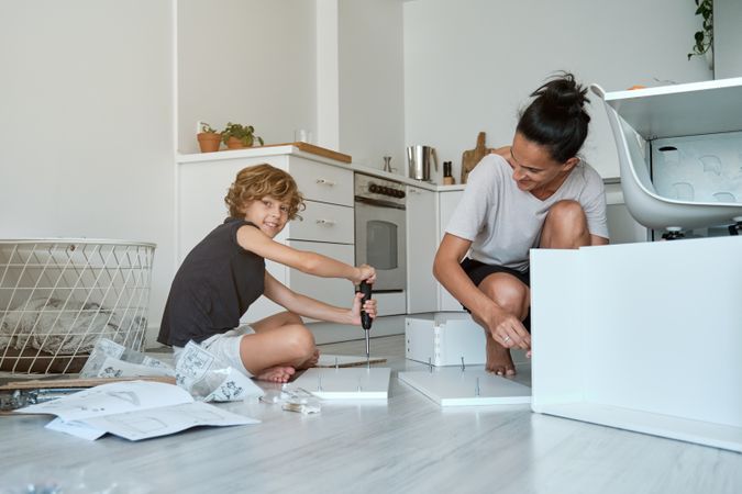 Happy mother and son assembling new furniture in kitchen