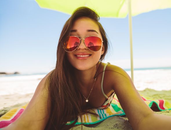 Close up of a smiling woman in sunglasses relaxing at a beach