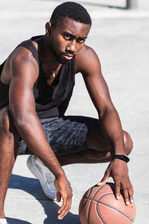 Confident Black sportsman on basketball court in summer