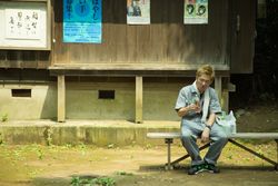 Man in work suit sitting beside plastic bag on wooden bench 5lKYN0