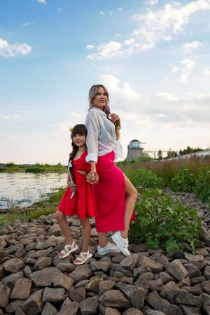 Mom and little daughter walking by the lake or pond