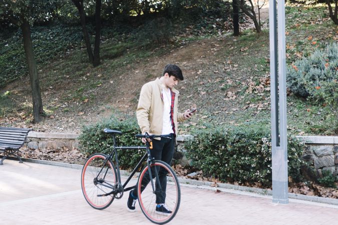 Man walking with bike while using mobile phone
