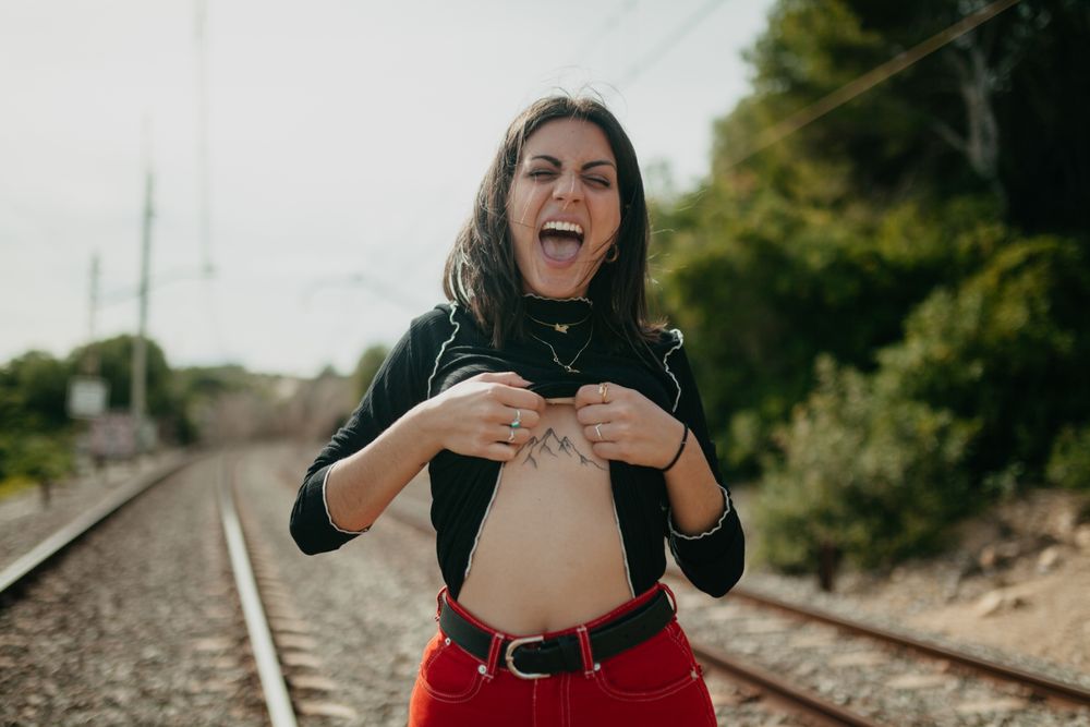 Excited woman showing tattoo on railway