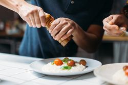 Man adding pepper to Italian dish