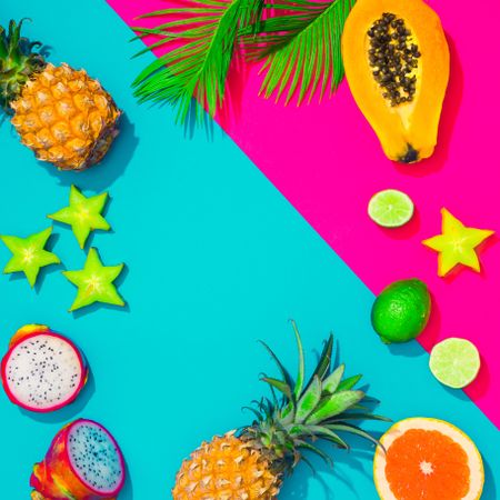 Tropical fruit, pineapple, papaya, dragonfruit on bright blue and pink background with palm leaves