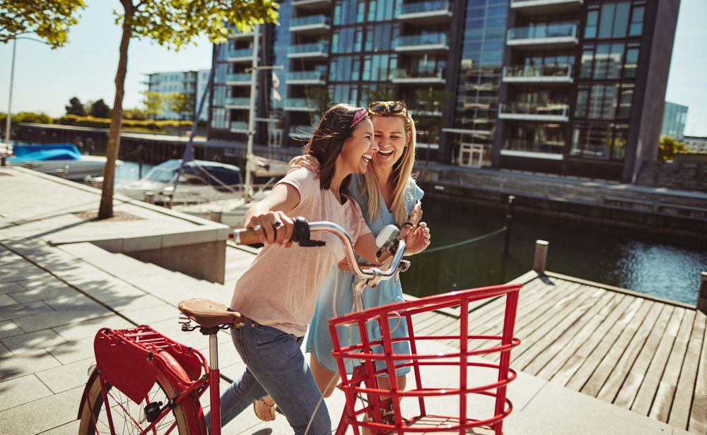 Two close friends laughing while walking and talking along the waterfront
