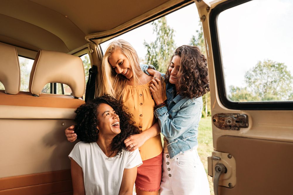 Group of friends hanging out in the back of a van on a road trip