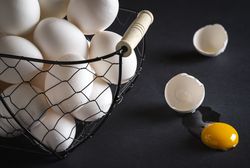 Cracked egg and basket full with chicken eggs