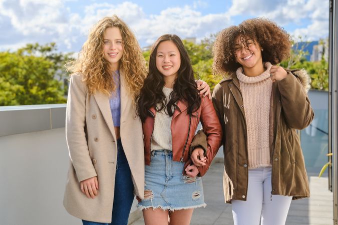 Diverse friends in autumn outfits standing on terrace