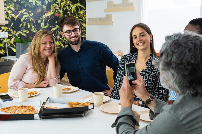 Content colleagues having lunch together and taking photo