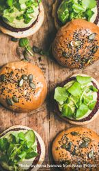 Fresh vegan burgers on seeded buns arranged on wooden board 5R2kR5