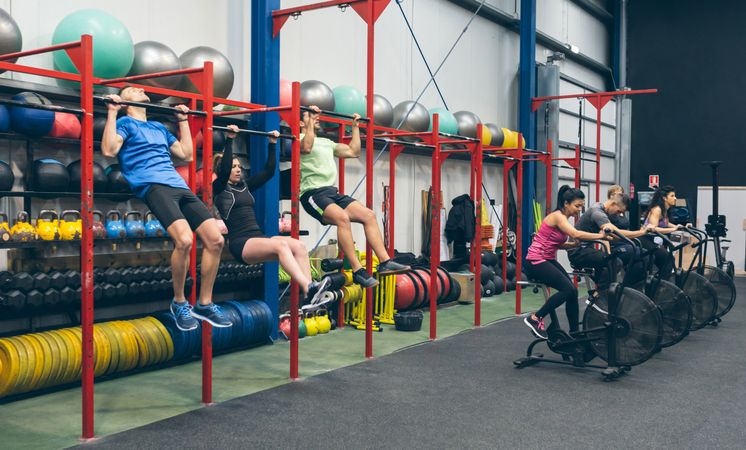 Athletes doing pull ups and air bike in the gym