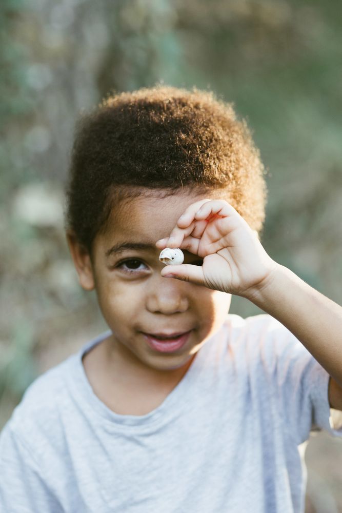 Black kid showing small seashell