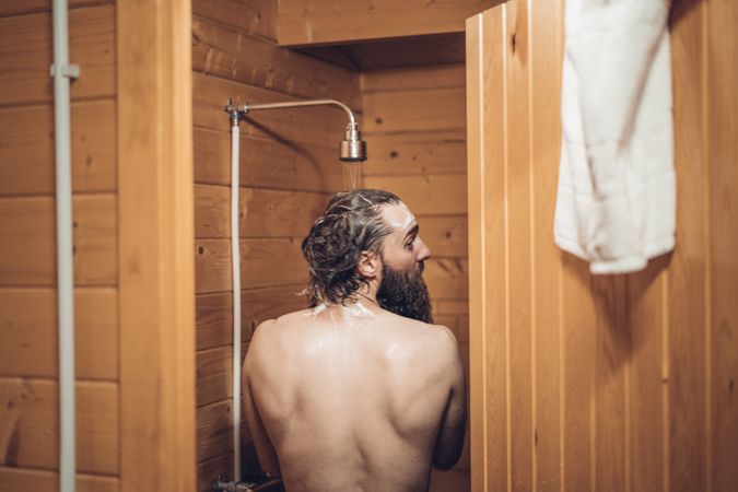 Man taking shower in wooden bathroom