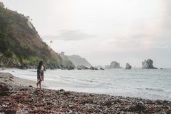 Woman with camera on shore near stones and water