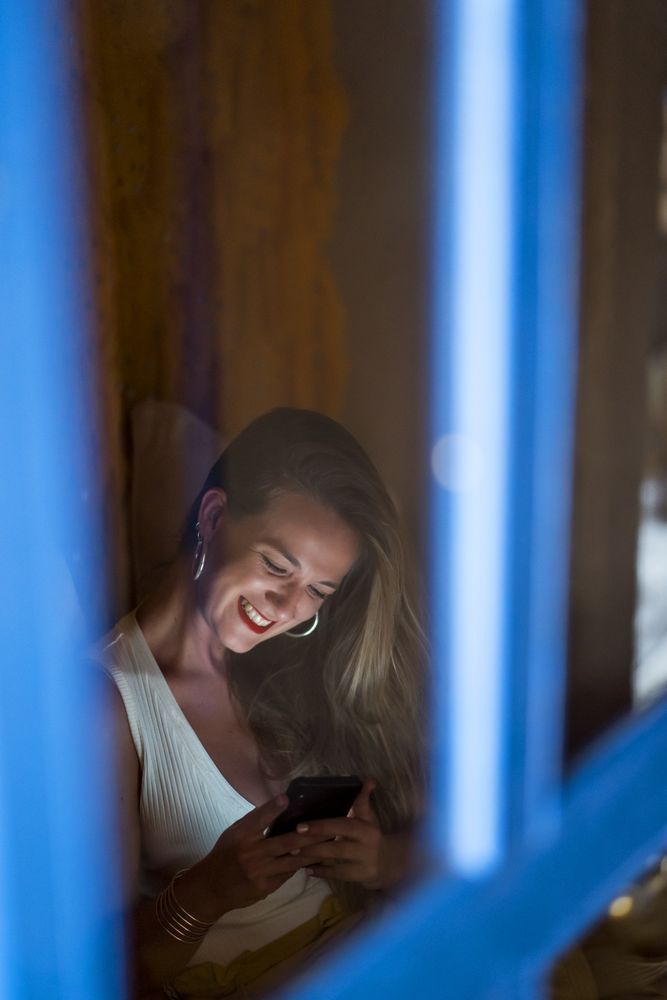 Smiling woman using smartphone in dark room