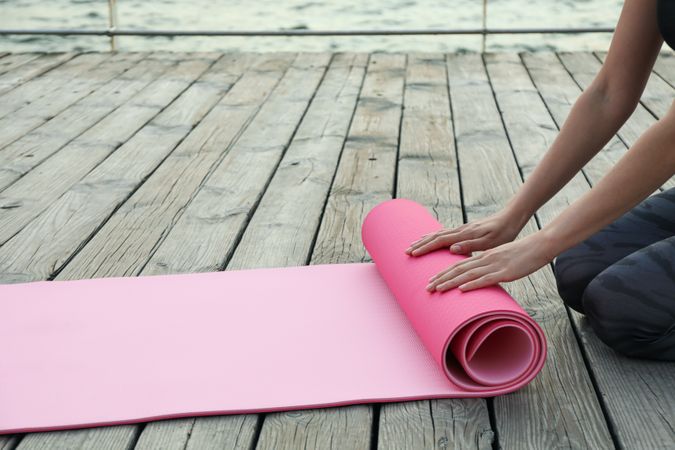 Yoga mat and female hands on wooden background