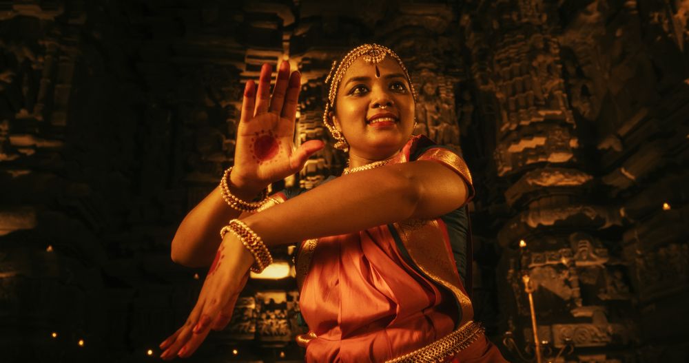 Young Indian Woman Dressed in Traditional Colorful Sari Gracefully Performs Bharatanatyam Dance in a Temple.