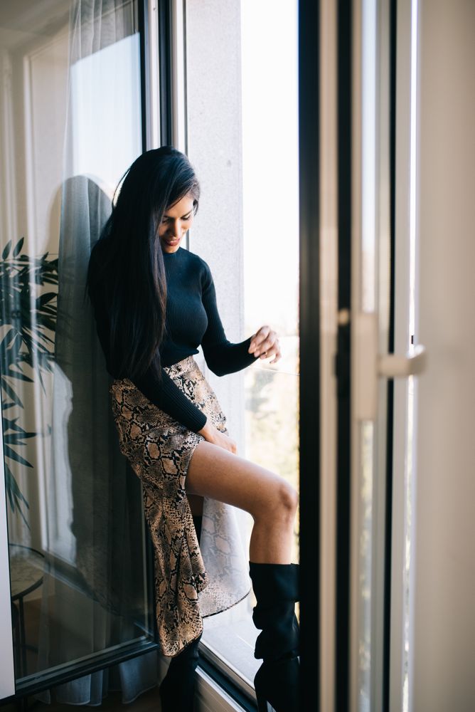 Stylist beautiful young Black woman standing near a big windows
